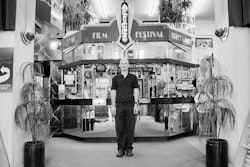 Definitely an obsession. Oh yes, from a very early age, maybe six or seven, I’ve been absolutely infatuated with the moving image. In fact, not just film itself but the places where film is shown – the cinemas, the architecture. Be it gaudy Victorian or Art Deco, I was always fascinated by it. And of course the magic of that beam of light from beyond the little window – the projection room. A projectionist, that’s what I did straight from leaving school. I was just waiting for the chance, it was all I wanted to be, but the careers advisor couldn’t see it. All he could say was that it was antisocial and the pay was poor. I thought, some careers advisor you are! I was no star pupil in the education field. I was a dreamer and so I knew the silver screen was the right place for me to be. I was hellbent on the world of fiction and its architecture. It was Laing Masters gave me my first break, at the Hollywood in Sumner. I got tremendous excitement from getting that film to them – the audience – making their lives different, even if it’s just for two hours. I always got a thrill from it. You don’t have to do drugs or alcohol to get away from it all – film is the clean way to get out of it. The overture, the lights, that whole wonderful performance that facilitates your entry into another world. My interest in films and cinema architecture has grown and grown over the years, and of course Alice’s, where I work now, is the perfect treasure chest for that. It’s important to me and it’s important to Christchurch. It’s an archive temple of film in a wonderful Deco building. It’s the passion of all of those who work here, an amalgam of our interests. I mean, it’s easily the best store in the country and we don’t even have to push that. Like any good place, it’s all word of mouth. All things to all people, that’s what it is. Little Johnny comes in looking for A Bug’s Life, but there’s the chance he’ll work along the shelf and come across Asterix. I get a tremendous thrill out of that possibility. The chance that new horizons may be opened up for you. I like the fact that working here we might help people expand in that way. I’m forty years old now and I come home each day absolutely buggered. The day is never less than a full-on adrenaline buzz. Everyone there from the owner down is totally dedicated. DVD is the big transition at the moment, and the goodies it brings to us make it an exciting time. I’ve always been in love with the tactileness of film – something I can feel and touch – but you have to say that this new technology is giving us all sorts of exciting alternatives, things that might not have been possible otherwise. I think discovery is the key word. That’s what film is all about. Certainly it’s the passion that keeps me here. Keeps that adrenaline pumping. I tell you, I love it.